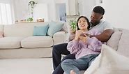Diverse couple sitting on couch and embracing in living room
