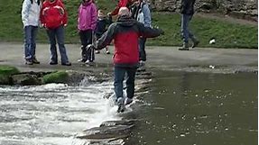 Crossing the wonderful Stepping Stones over the River Dove at Dovedale Derbyshire England UK