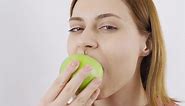 Close-up portrait of woman eating green apple. Eat fruit. Close-up of woman eating green apple.