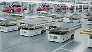 Automated Guided Vehicles with Electric Car Battery Packs inside Modern Automotive Factory. EV Production Line on Advanced Factory. High Performance Electric Car Autonomous Manufacturing Processes
