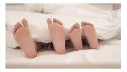 Children's feet moving under blanket. Kids are lying in bed.
