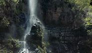 Beautiful tropical waterfall illuminated by the sun falls on a mossy rock - Free Stock Video