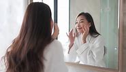 Premium stock video - While looking in a mirror, a woman examins her healthy skin