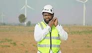 Engineer african american man uniform working in the wind turbine area, wearing white hard hat