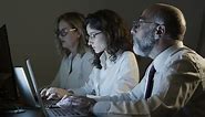 Premium stock video - Overworked coworkers using laptops in dark office