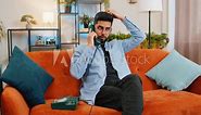 Portrait of young Indian man making telephone conversation with friends sitting on comfortable couch at home. Happy excited Hispanic guy enjoying old-fashioned retro phone from 90s talking indoors