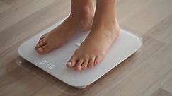 Woman On Scales Measure Weight.Human Barefoot Measuring Body Fat Overweight.Girl Legs Step On Bathroom Scale. Slimming Woman Checking BMI Weight Loss. Diet Female Feet Standing Weighing Scales On Room