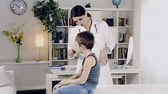 Female doctor examining young boy in her office