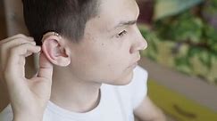 the young man wears a hearing aid. Man with hearing aid
