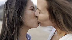 Happy gay women couple kissing together outdoors. LGBTQ lesbian love and relationship concept