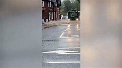 Lorry drives through a flood pushing excess water into a pub as Storm Babet hits.