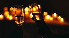 Backlit shot of couple toasting champagne flutes and kissing in candlelight