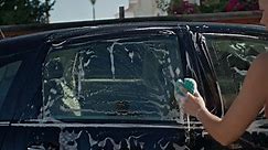 Auto Cleaning and Detailing: Woman Washes Car with Foam Sponge at Home Yard. High quality 4k footage