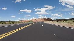 POV Driving a car on curvy asphalt Arizona road with rocky mountains near Grand Canyon. Blue sky with white clouds