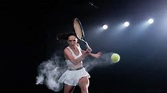 Aesthetic Shot of an Athletic Female Tennis Player with a Black Background Hitting a Low Ball Under Spotlights. Cinematic Super Slow Motion Captures a Winning Strong Forehand Shot with Smokey Effect