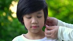 Mother Inserting Hearing Aid In The Ear Of Her Son