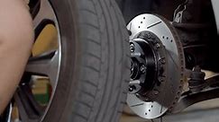 Installing a car wheel 4K60P .Car wheel replacement in workshop.Using a impact tool wheel spanner to tighten lug nuts of a car front wheel.Mechanic installs and screws on the car.
