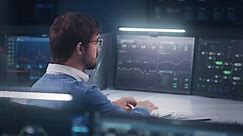Professional software engineer sits in front of computer with big data server and blockchain network, works in modern monitoring control room with real-time analysis charts. Concept of cyber security.