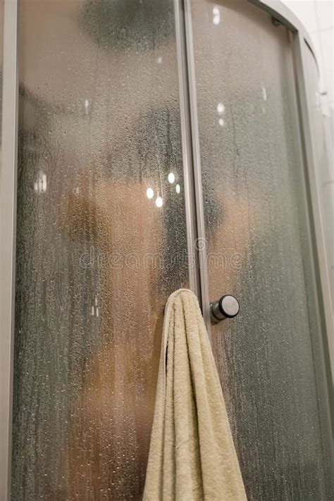 beautiful woman in the shower behind glass with drops