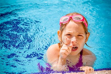 Śliczna gniewna mała dziewczynka bawić się w pływackim basenie zdjęcie