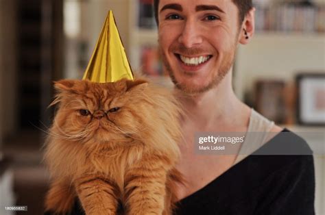Man With Grumpy Orange Cat Wearing A Party Hat High Res