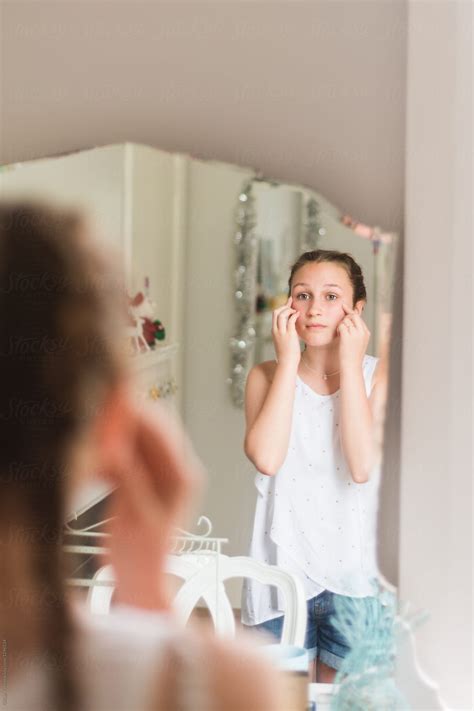teen girl looking at her reflection in the mirror by gillian vann