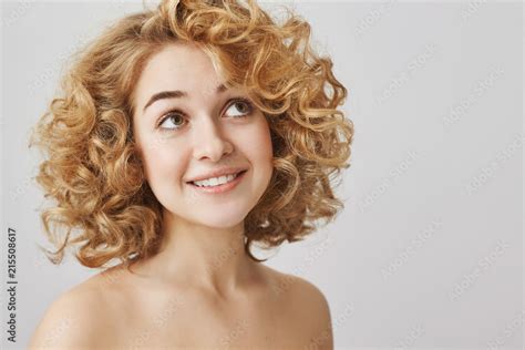 Tender And Cute Curly Haired Blonde Female With Bright Smile Standing