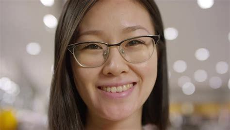 face of smiling chinese girl in glasses posing indoors by pressmaster
