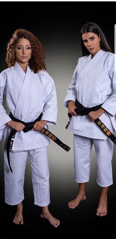 Two Women In White Karate Uniforms Standing Next To Each Other With
