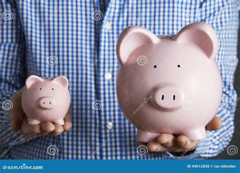 man holding large  small piggy bank stock photo image  person forties