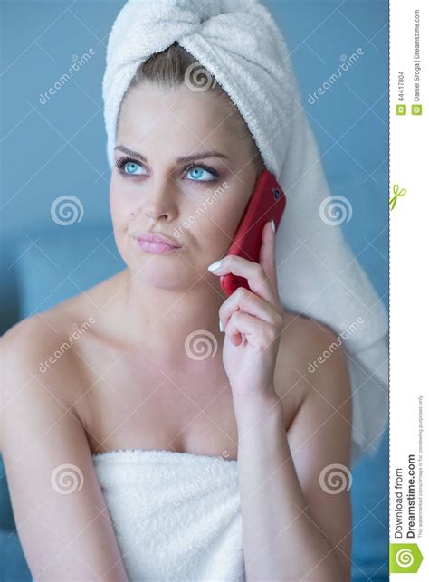thinking woman in bath towel with red cell phone stock