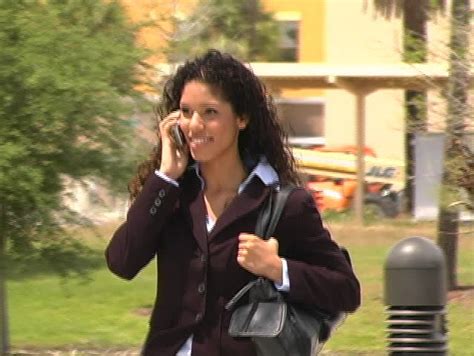 a beautiful latina brunette walking on a sidewalk talking on her cell phone stock footage
