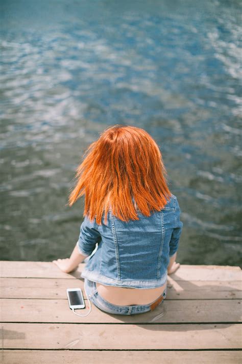 Red Hair Young Girl Sitting On A Dock From Behind By Alexey Kuzma