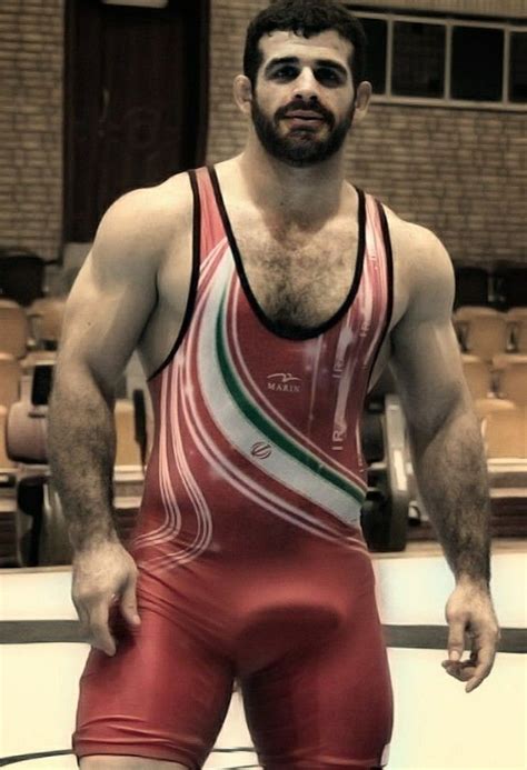 A Man In Red And White Wrestling Suit Standing Next To A Wall With