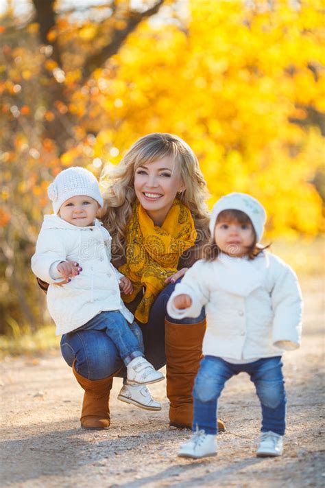 mamma e due bambine che camminano nel parco in autunno