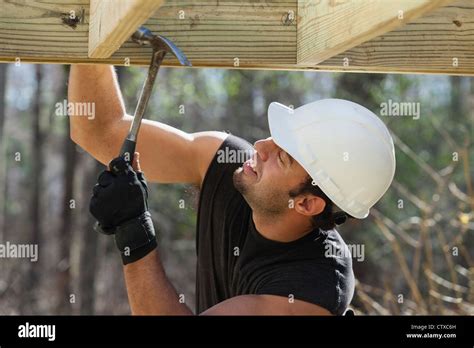 Hispanic Carpenter Nailing Pressure Treated Deck Joist With Hammer