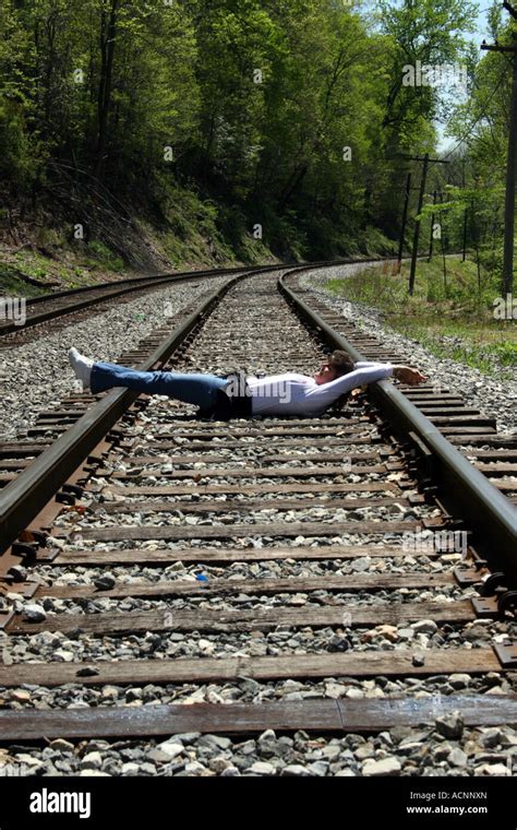 mujer acostada sobre las vías de ferrocarril con las manos y los pies