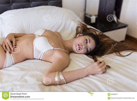 beautiful brunette woman lying in bed in sensual lingerie