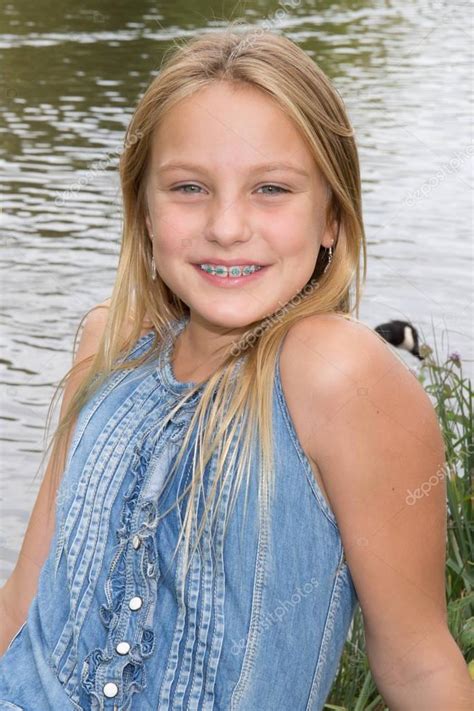 blond preteen girl in blue dress close up summer photo on the green