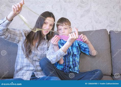 Mom And Son Are Playing With Slime Sitting On The Sofa Looking Through