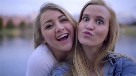 selfie style portrait of two two teen girl friends sticking their tongues out at the camera