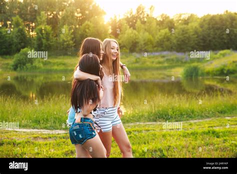 three beautiful girls walking and laughing on sunset in the park