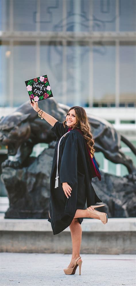 A Woman In Black Graduation Gown Holding Up A Sign