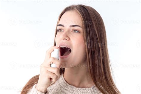 Young Girl Squirting Sore Throat Spray Is Isolated On A White