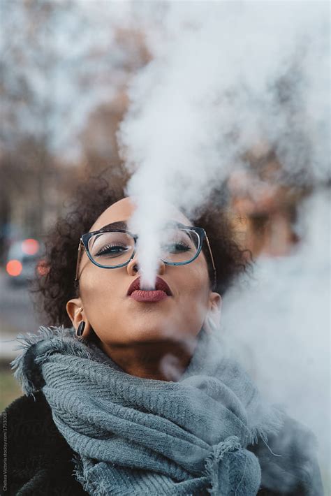 A Woman Blowing Smoke Out Of Her Mouth By Stocksy Contributor