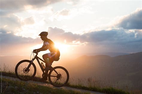 man riding  bike uphill  sunset sky stocksy united