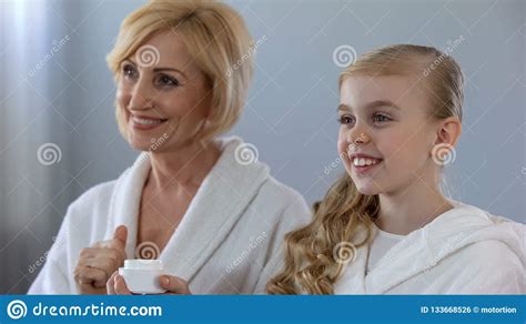 oma en kleindochter glimlachen die van glanzende huid na
