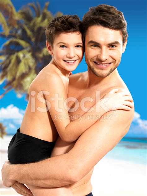 happy smiling father hugs son at tropical beach stock