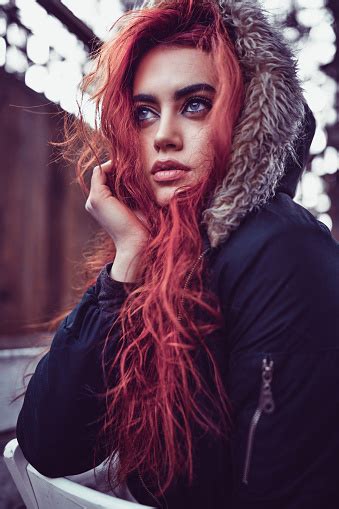 beautiful female redhead sitting on chair and warming up in autumn