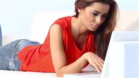 Sexy Woman In Red Dress Lying And Working On Laptop